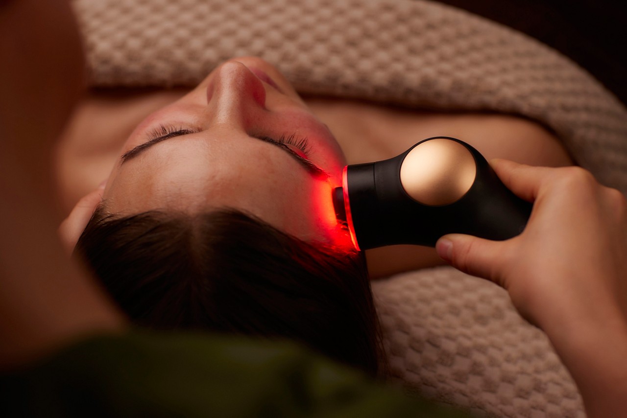 Spa therapist giving a woman a Theraface microcurrent facial treatment.